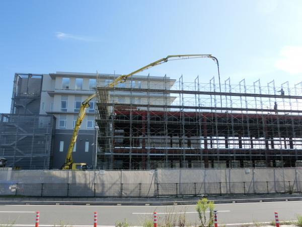 健診センター建設工事、ポンプ圧送車が屋上にコンクリートを流し込む様子